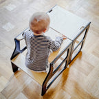 Child sitting at a small table on a wooden floor