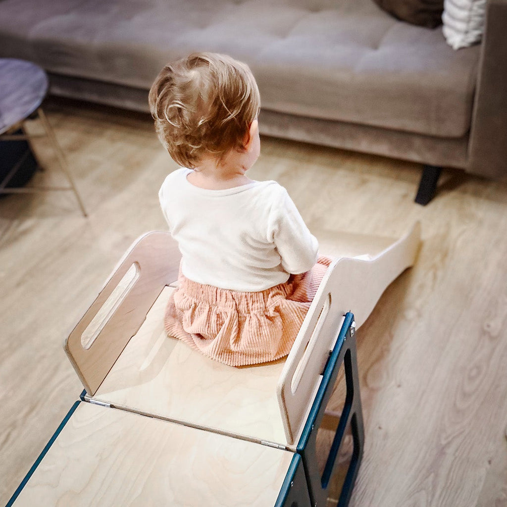 Child sitting on a small wooden stool in a living room.